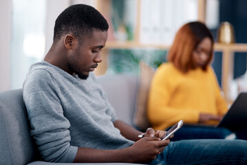 Relax, phone or technology addiction and a black man on the living room sofa of his home with his girlfriend on a blurred background. Mobile, contact and social media with a male person in a house