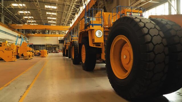 An assembly line of large dump trucks. Assembled trucks stand in a row in the production hall. Production of large yellow mining trucks BelAZ
