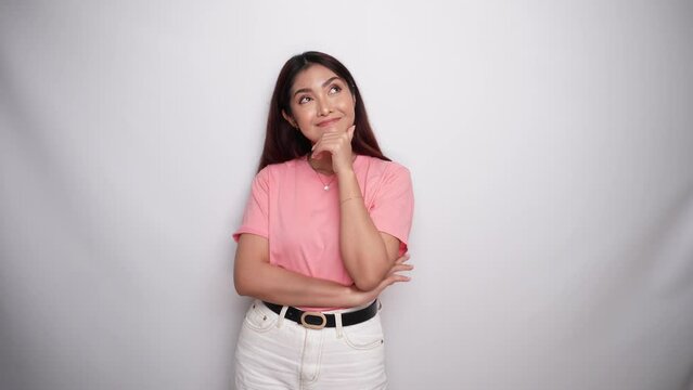 Thoughtful young woman is wearing pink shirt while looking aside in Studio with White background