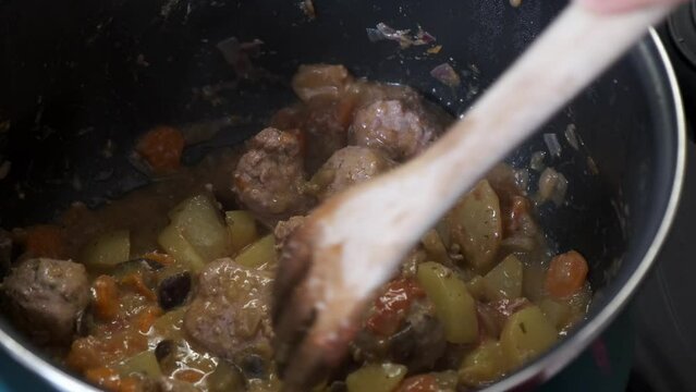 Close-up of preparation of a dish of traditional vegetable stew with meat balls in a pot
