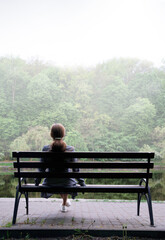 Lonely girl on a bench by the lake
