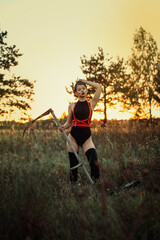 a girl in a black bodysuit stands in a field at sunset