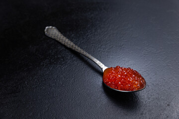 A spoon with red caviar on it 