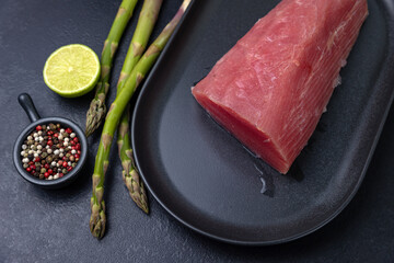 A plate of raw tuna with asparagus and lemons

