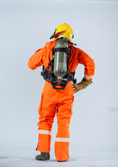 The professional firefighter is standing with his back turned wearing an oxygen tank on his back while looking sideways with confident on a white background.