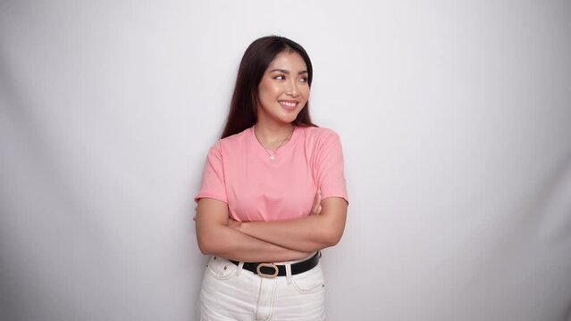 Confident smiling Asian woman dressed in pink, standing with arms folded and looking at the camera in Studio with White background