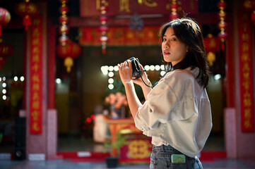 Attractive Asian woman with her camera visits a beautiful Chinese temple during her trip