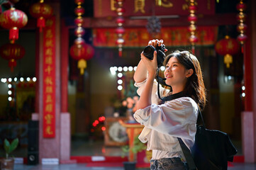 A female tourist enjoys taking photos in a beautiful Chinese temple on her vacation.