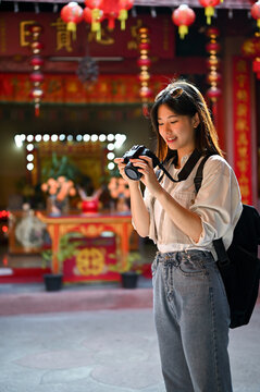 A female tourist checking photos on her camera, visiting a Chinese temple in the old town