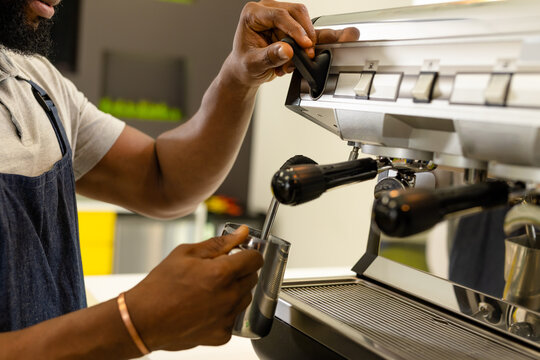 Midsection of african american male barista making coffee with maker at coffee shop