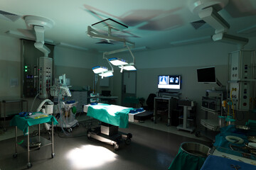 General view of operating theatre at hospital, with operating table and equipment in low light