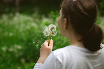Summer joy - lovely girl blowing dandelion