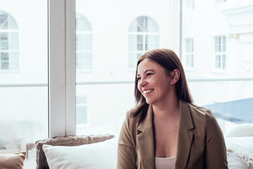 Fototapeta premium Portrait of a beautiful young smiling woman looking away. Concept of wellbeing and self-care