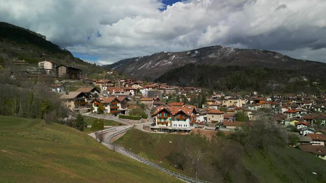 Aerial panoramic view of San Lorenzo in Banale village with Dolomites mountains of Trentino Alto Adige in background, Italy
