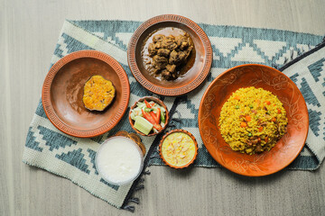 Haash Bhuna Khichuri Combo with egg plant, korma karahi, meat, salad, borhani and firni served in dish isolated on mat top view of indian and bangladeshi food