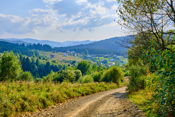Fototapeta na wymiar landscape dirt road in the mountains with a turn. Blue mountains background. Sunny weather in the Carpathians