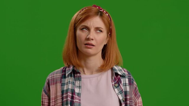 Woman expressing hesitation feels puzzled and unamused on isolated on green screen background. Displeased female rolling her eyes.
