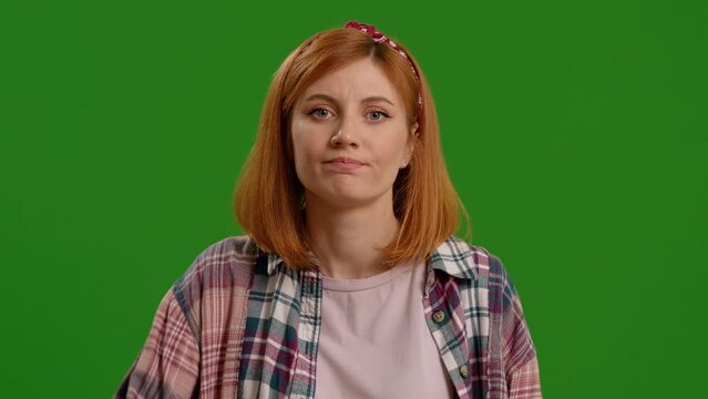 Frustration demonstrated by an woman tapping forehead as stupidity sign isolated against green screen scene. Judgmental expresion to someone being silly.