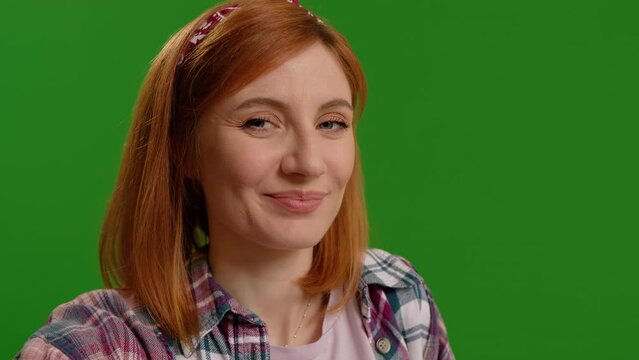Smiling surprised woman receiving compliments while on video call over light green background. Facial expression while listening to congratulations.