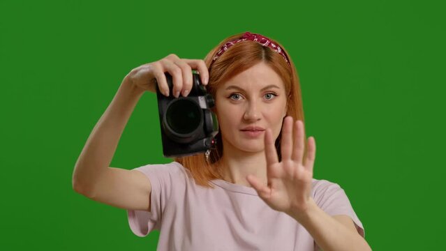 Close up of female photographer using camera taking picture while standing on green screen background. Professional female photographer with taking photos in studio Creative industry jobs concept.
