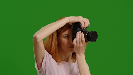 Side view of female photographer taking picture enthusiastically while standing on green screen background. Pleased photographer with the shooting on workplace. - Powered by Adobe