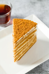 Layered honey cake slice on white porcelain plate on stone background Medovik