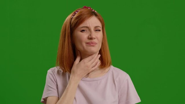 Young redhaired female with sore throat over isolated green background. Woman having symtoms of flu or cold. Healthcare concept.