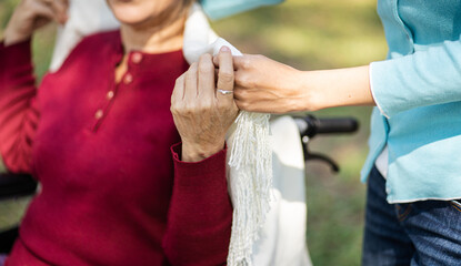 Family relationship Asian senior woman in wheelchair with happy daughter holding caregiver for a hand while spending time together