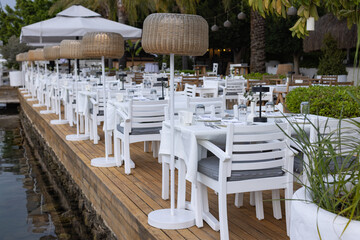 Summer terrace of Mediterranean restaurant, popular travel destination near sea with hipster tables and chairs. 