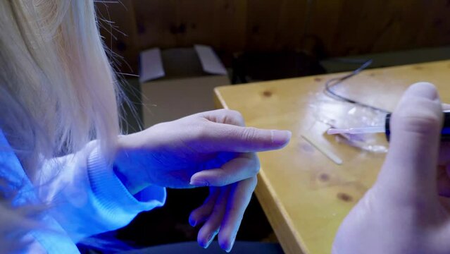 una ragazza prepara con cura lo smalto per le unghie prima di inserire la mano nel forno per asciugarle
