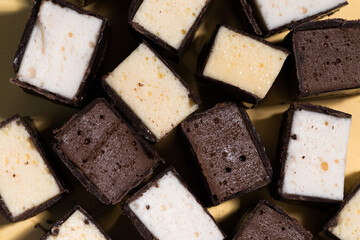 cut chocolate candies with different fillings lies on the yellow table. 21 april 2023. Russia.