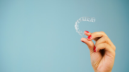 Young Asian Indian woman holding removable invisible aligner, also known as invisalign or  clear...