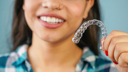 Young Asian Indian woman holding removable invisible aligner, also known as invisalign or  clear aligner - obrazy, fototapety, plakaty