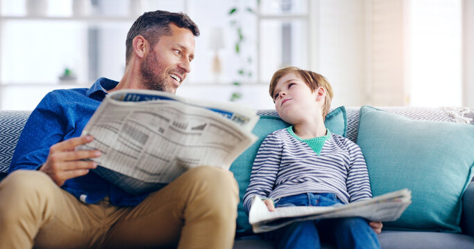 Father, child and reading newspaper on sofa relaxing together in the living room at home. Happy dad and kid enjoying the news in relax on lounge couch for knowledge on weekend or holiday at the house