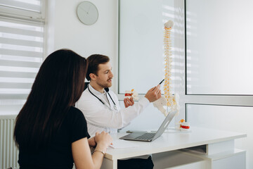 Female patient talking to doctor about her problems with her back during consultation in the...