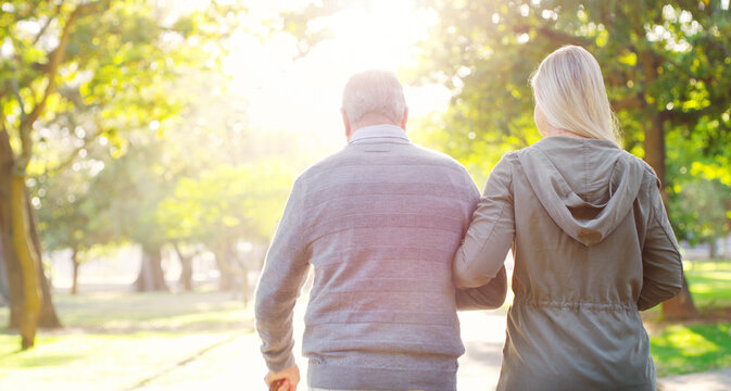 Senior man, woman and walking outdoor in a park for support, love and care. Back of elderly father with a cane and daughter on walk for a healthy retirement, life insurance and family time in nature