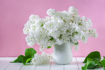 Bouquet of white lilac flowers in vase on pink background