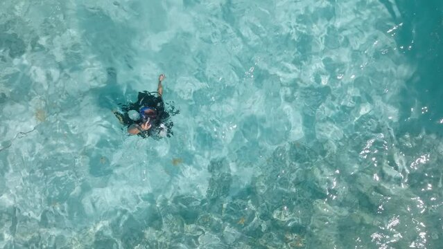 Male scuba diver deflates BCD to submerge himself under tropical water