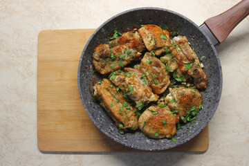 Fried chicken with herbs and garlic on frying pan