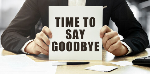 Businessman holding a white card with text Time to say goodbye on office background