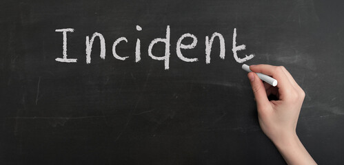 A woman's hand write text incident with chalk on chalkboard