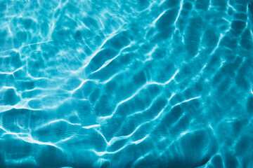 Abstract nature textured background, water waves in the pool with sun reflection, clear blue water