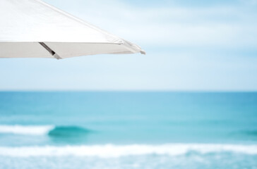 Closeup umbrella on the beach and foam of sea wave.