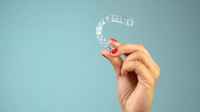 Young Asian Indian woman holding removable invisible aligner, also known as invisalign or  clear aligner