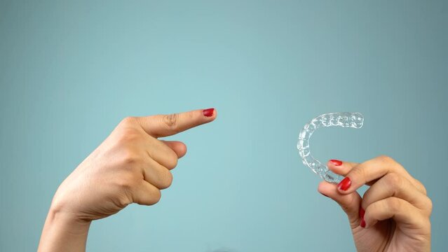 Young Asian Indian woman holding removable invisible aligner, also known as invisalign or  clear aligner