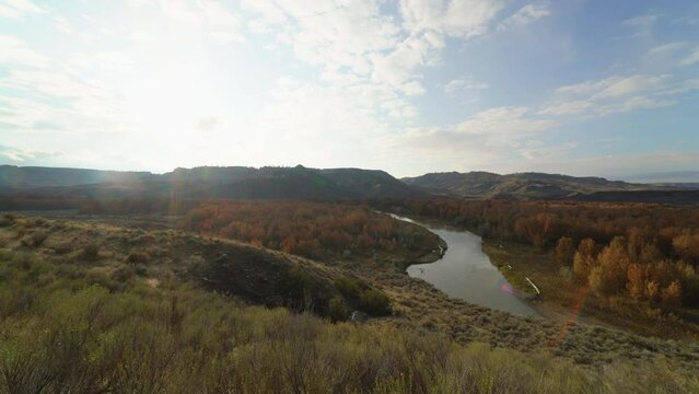 Setting sun over river valley breaks in autumn foliage