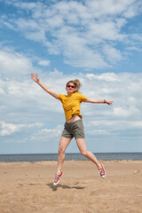 Obraz premium Cheerful young woman having fun and jumping on the sand