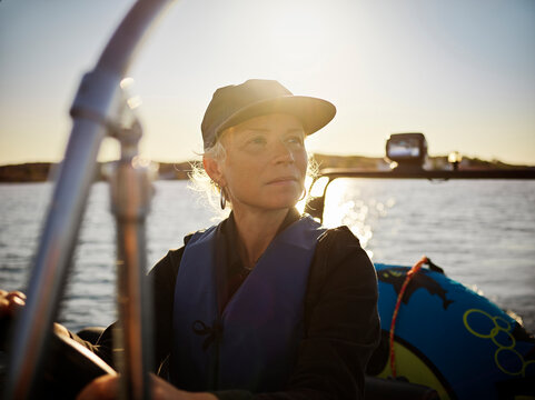Woman driving boat on sea during sunset