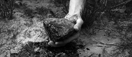 Bloodied hand with big stone