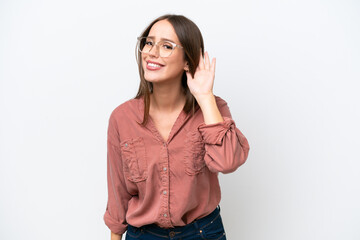 Young pretty caucasian woman isolated on white background listening to something by putting hand on the ear